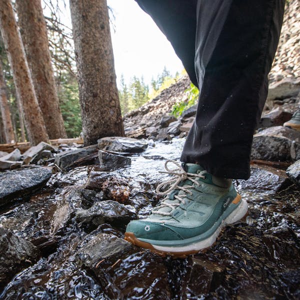 Walking across a stream in the women's waterproof Oboz Hyalite hiking shoes.