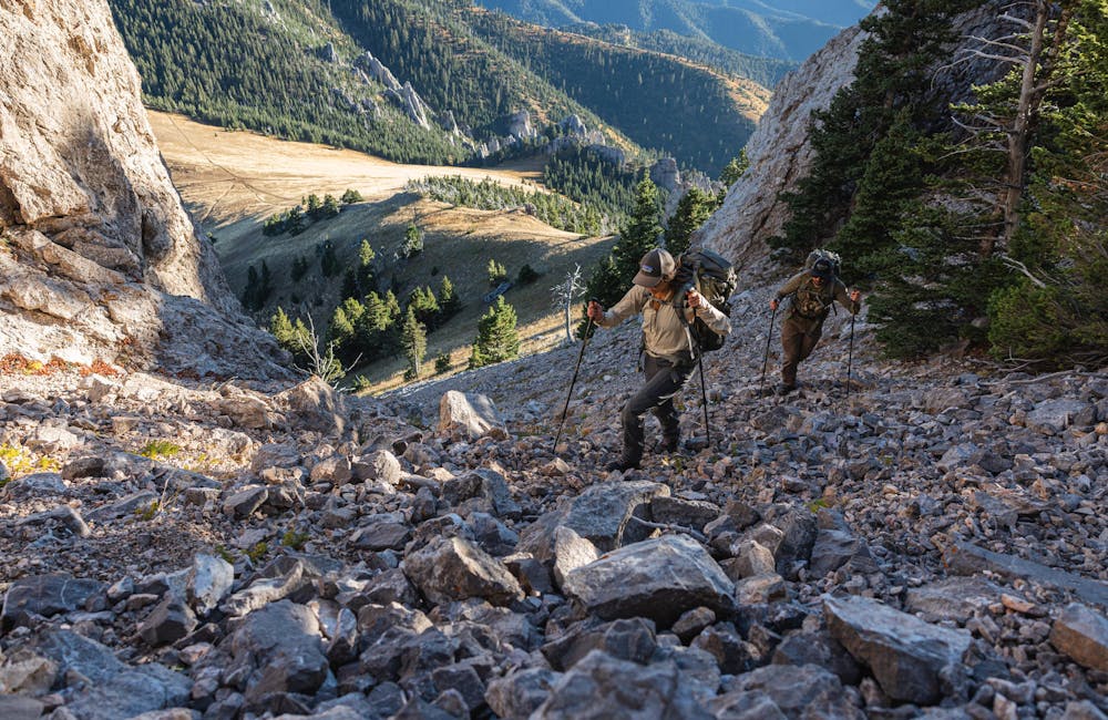 Two hikers navigate through a rock field on a hike in Montana.