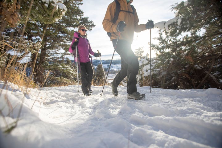 A couple is walking on a snowy path in Oboz Bangtail snow boots.