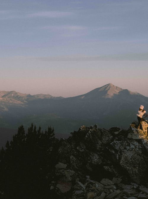 Two people hiking on a ridge at sunrise with mountains in the background.
