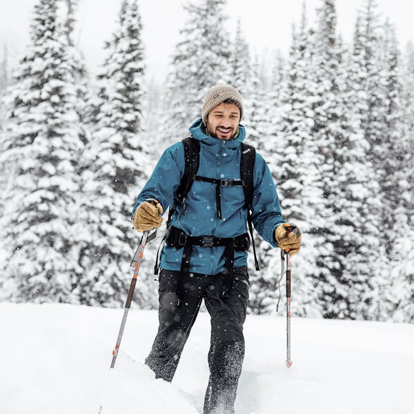 Hiker traversing through snowy forest in Oboz winter boots.