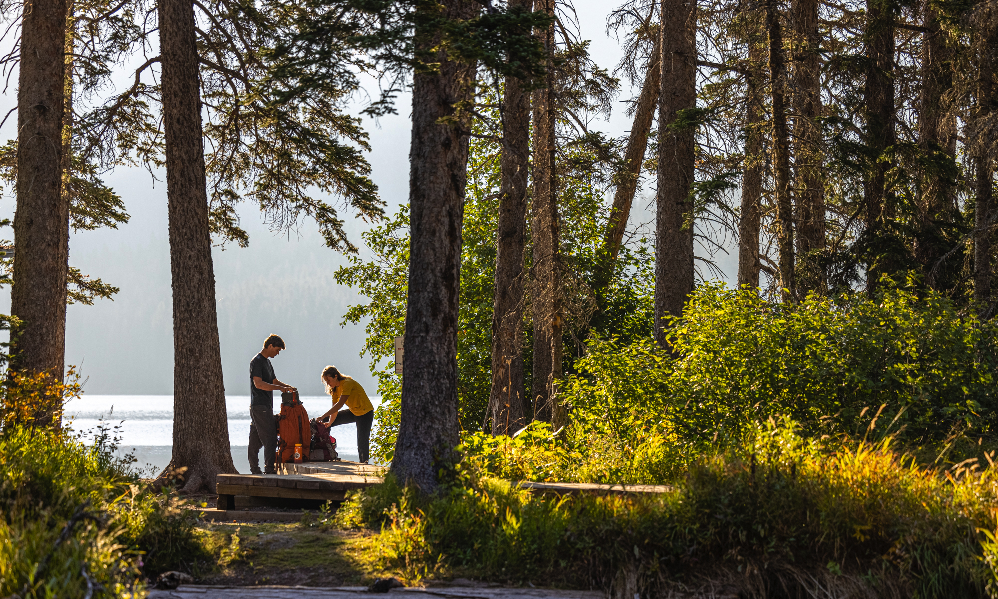 Two hikers packing their backpack before a trek.