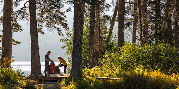 Two hikers packing their backpack before a trek.