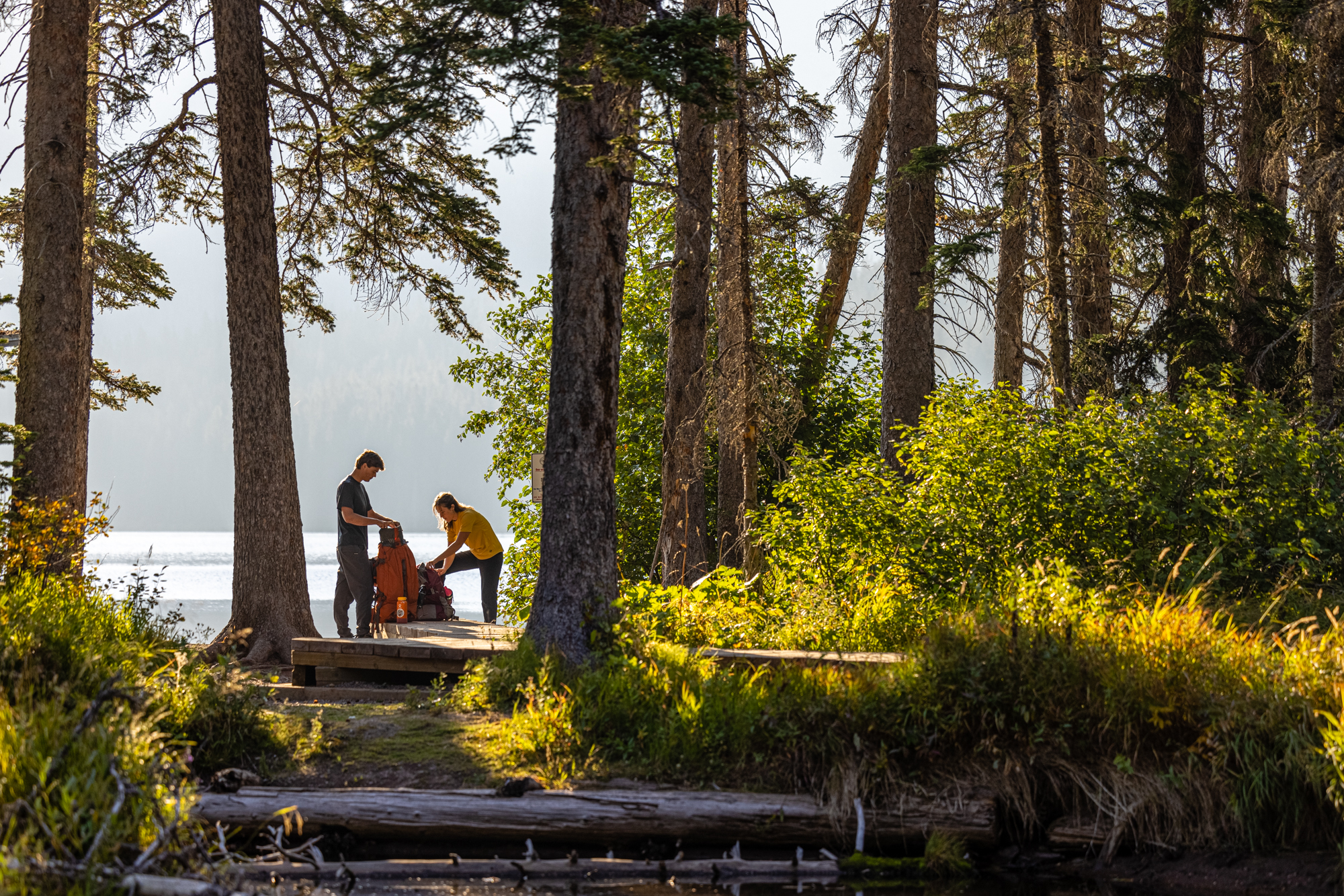 Two hikers packing their backpack while wearing Oboz hiking boots