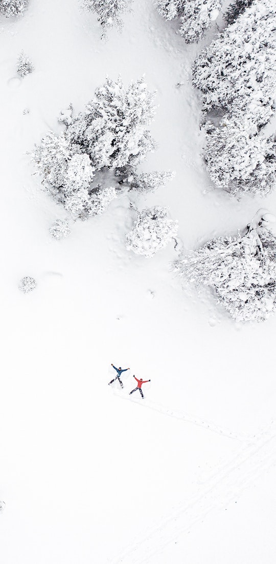 Two people making snow angels in the forest during wintertime