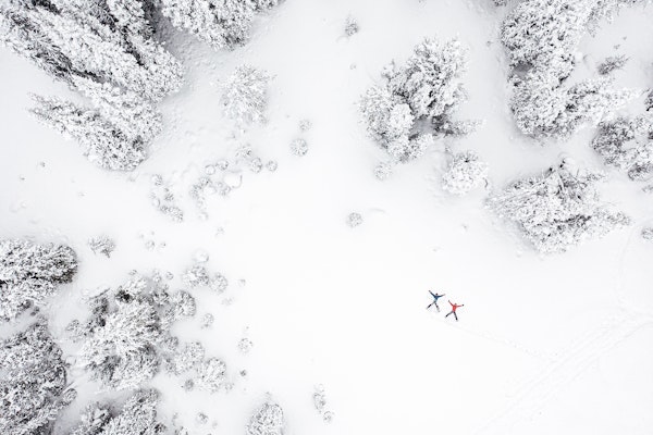 Two people making snow angels in the forest during wintertime