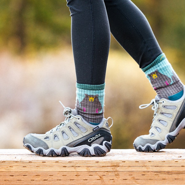 Women walking on a wooden bridge in the Oboz Sawtooth II Low hiking boots.