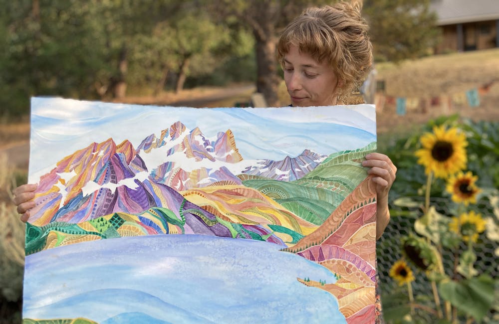 Oboz Trailblazer Ayla Mae Wild holding one of her paintings.