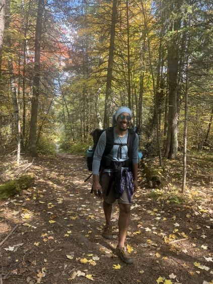 Person walking through a wooded area with backpacking gear