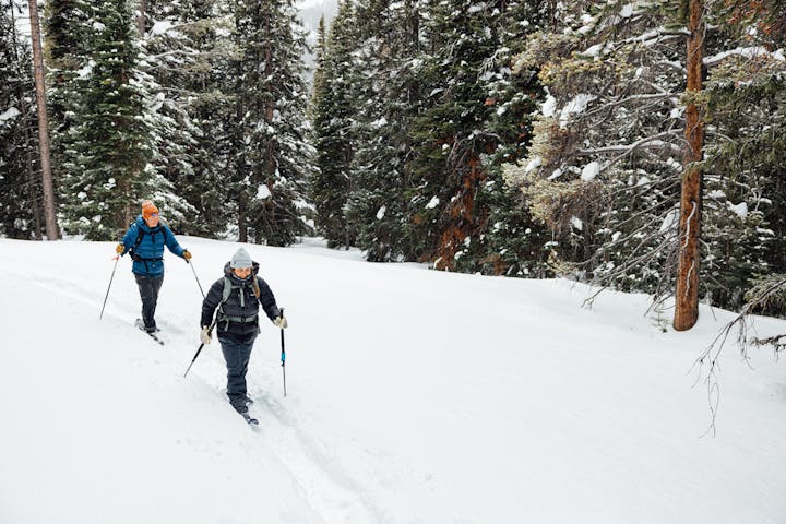 Snowshoers traverse through a snow covered trail in the forest while wearing Oboz winter boots.