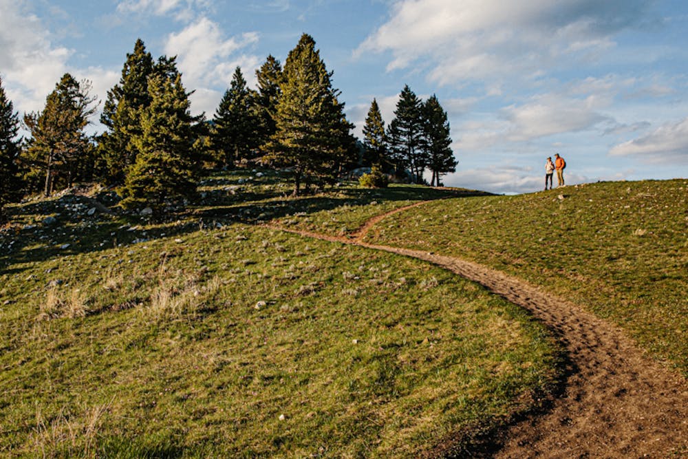 Two hikers wearing Oboz hiking shoes stopped at a fork in the trail on a sunny day