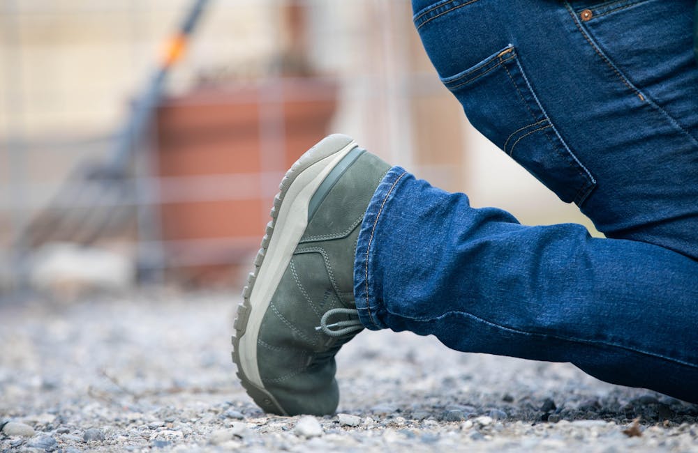 Man kneeling on gravel patio in Oboz Shedhorn casual boots.