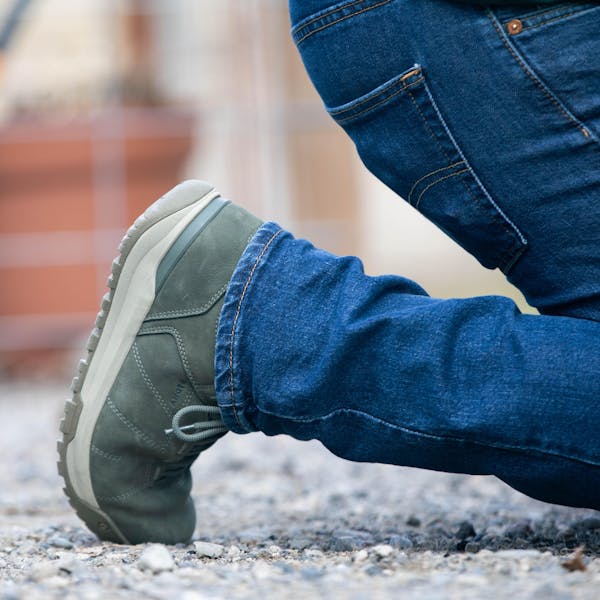 Man kneeling on gravel patio in Oboz Shedhorn casual insulated boots.