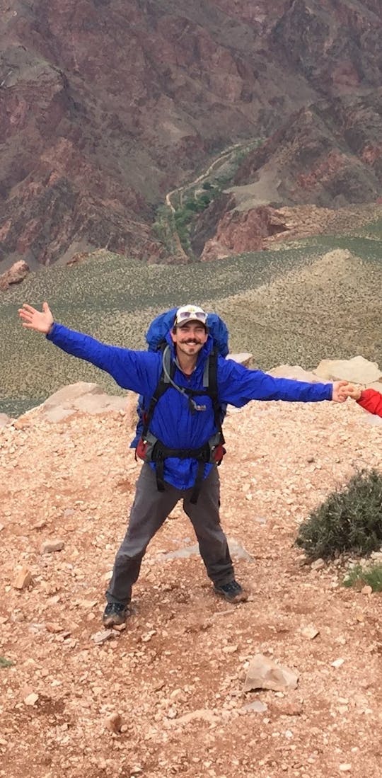Two stoked adventurers wearing Oboz hiking boots at the top of the mountain landscape.