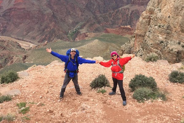 Two stoked adventurers wearing Oboz hiking boots at the top of the mountain landscape.