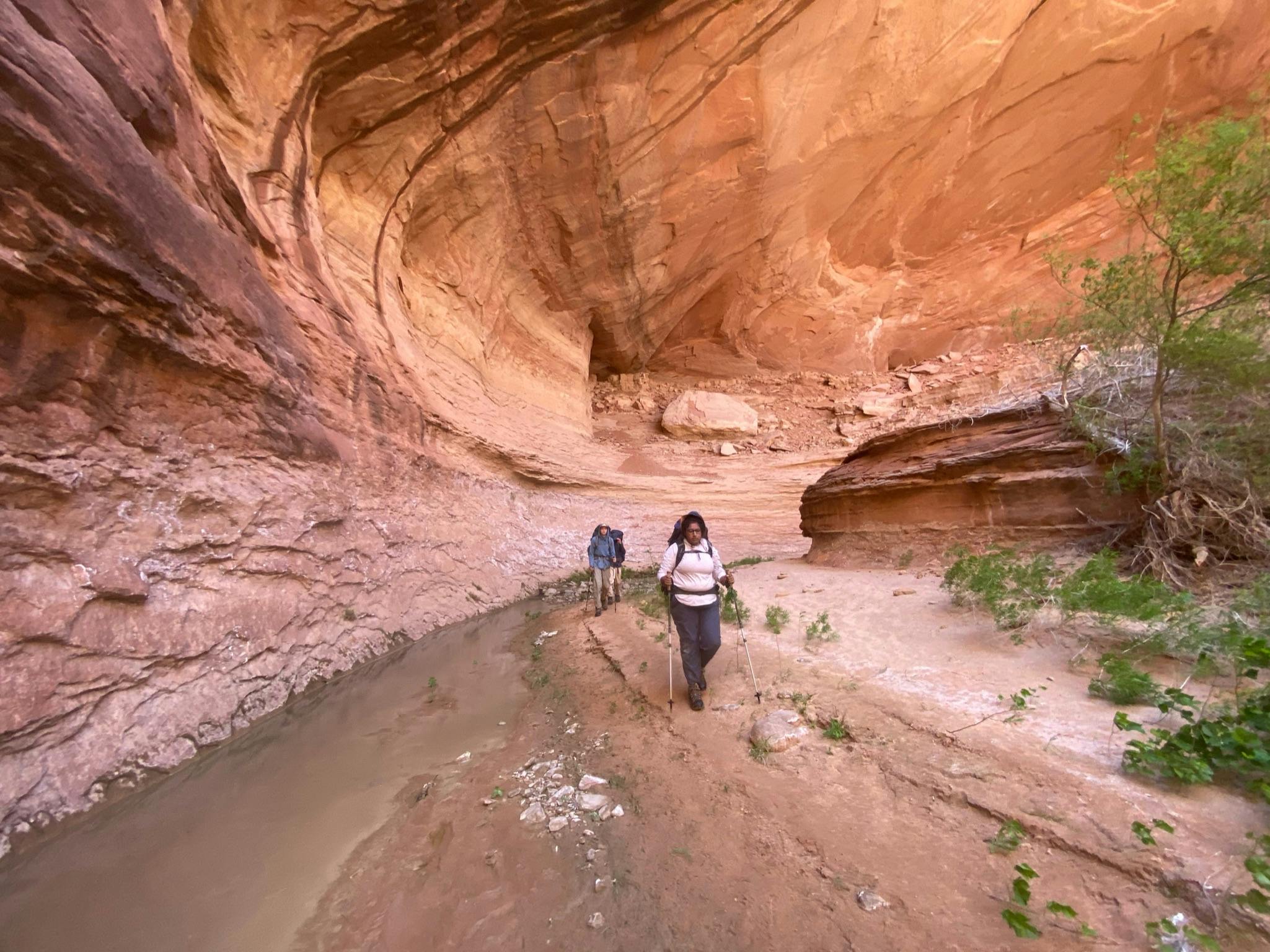  Joe St. Onge hiking in the desert under a red rim of rock.