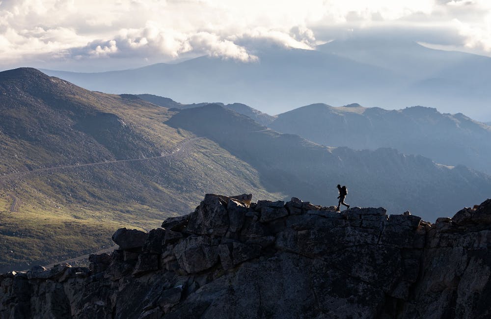 Oboz Footwear Trailblazer Evan Gill scrambling across a ridgeline.