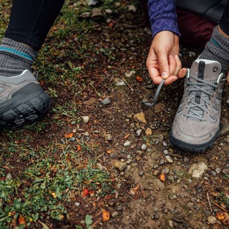 Oboz Sawtooth X being tied by a hiker on the trail.