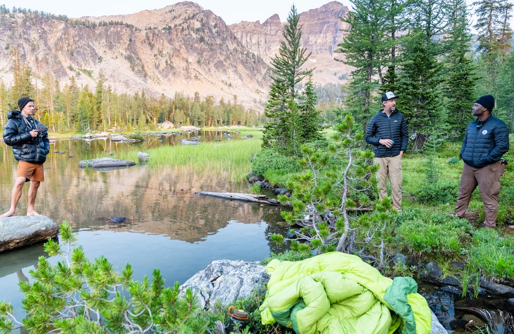 A group of backpackers talking at a mountain lake in Montana.