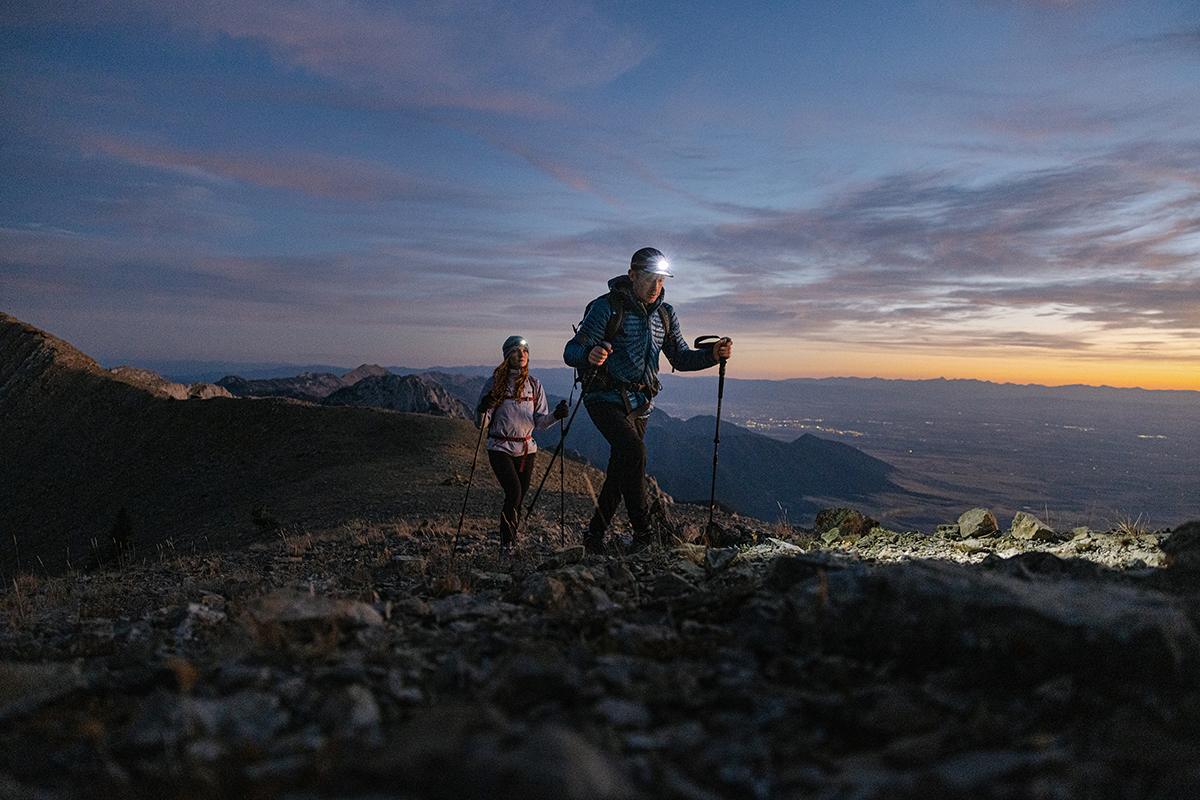Two people hiking with headlamps and Oboz footwear.
