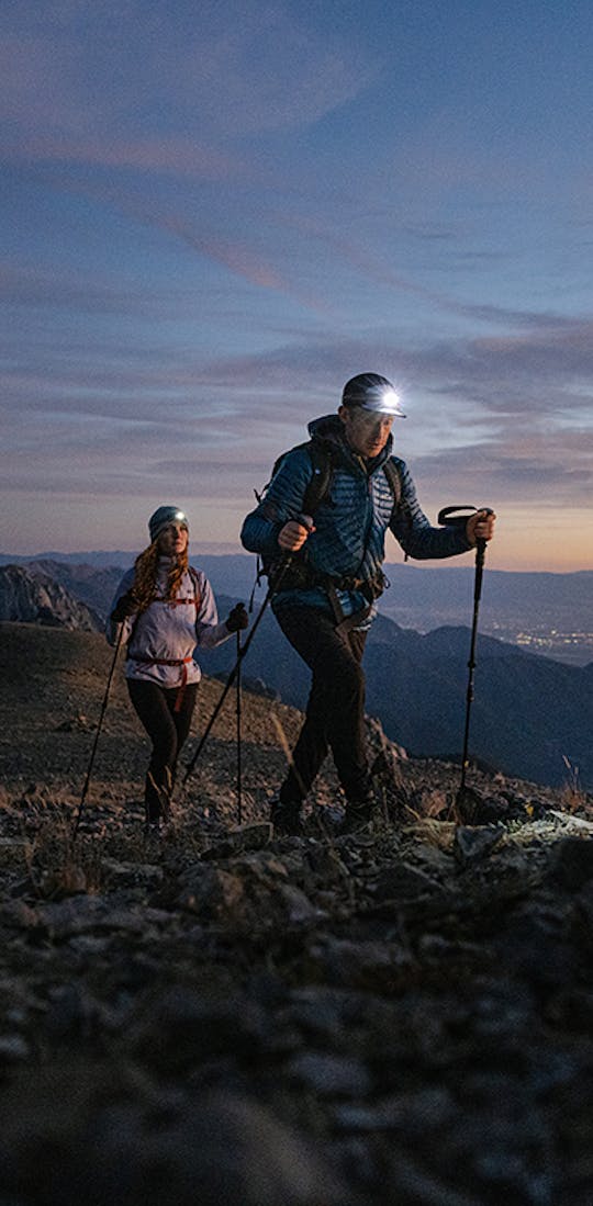 Two people hiking with headlamps and Oboz footwear.