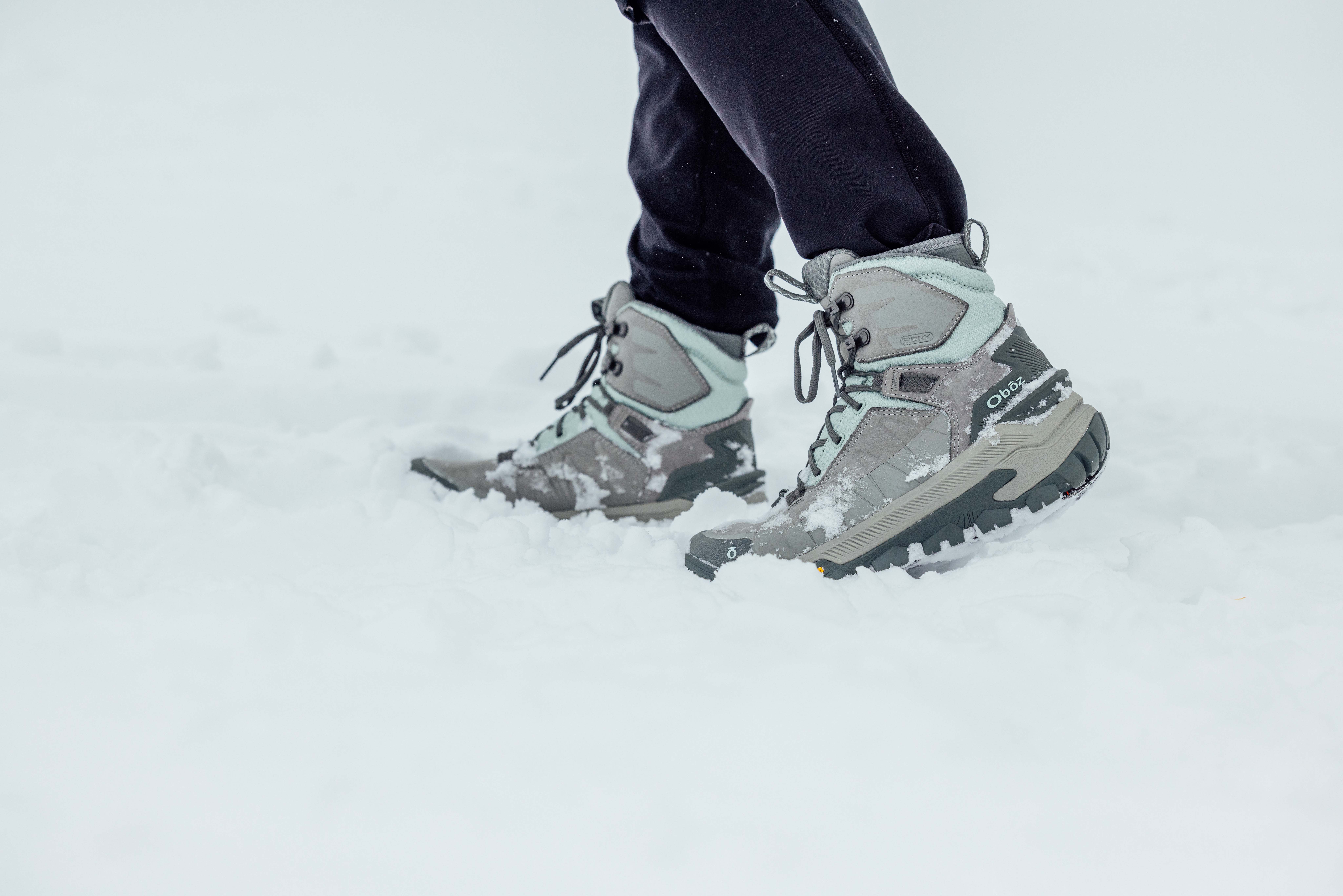 Woman hiking in Oboz winter boots across snowy winter path.