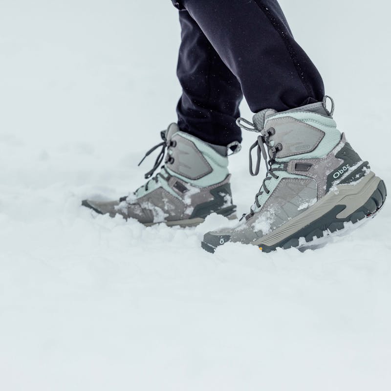 Woman hiking in Oboz winter boots across snowy winter path.