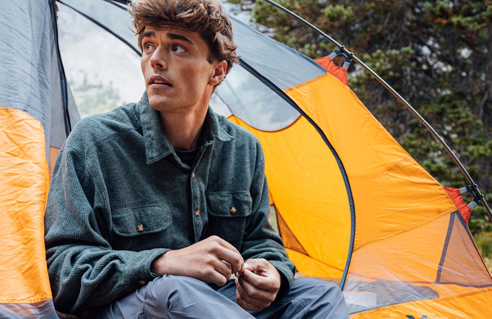 Man relaxing in his tent at a camp site.