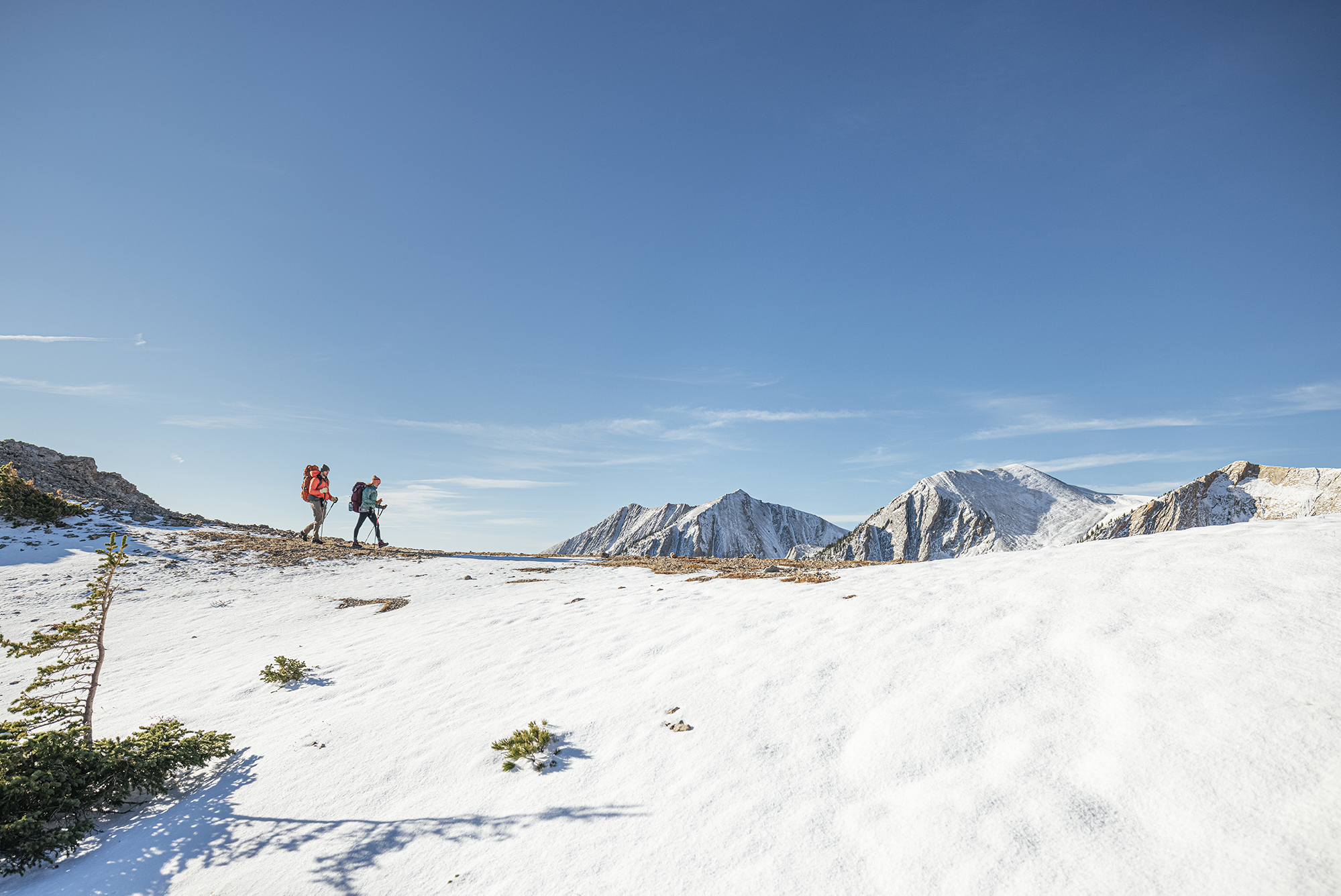 Two people wearing the Bridger Mid Waterproof hiking boots in the snowy high alpine.