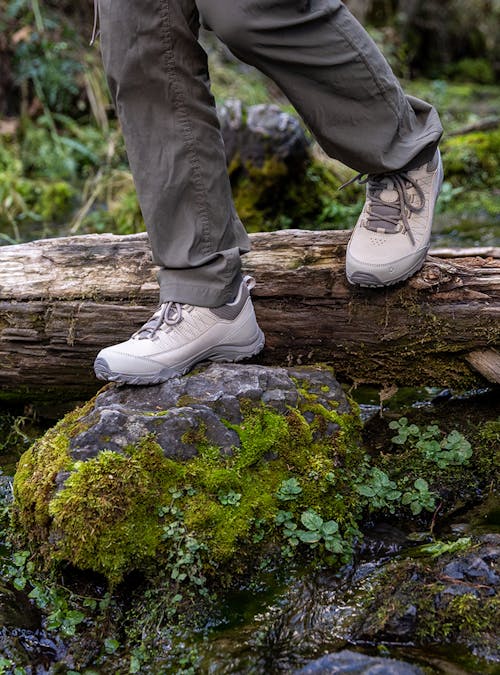 The Oboz Ousel Low hiking boot stepping on a mossy rock.