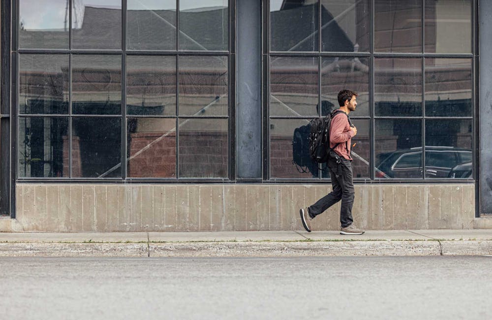 Man walking on an urban sidewalk in the Oboz Bozeman Low casual shoes.