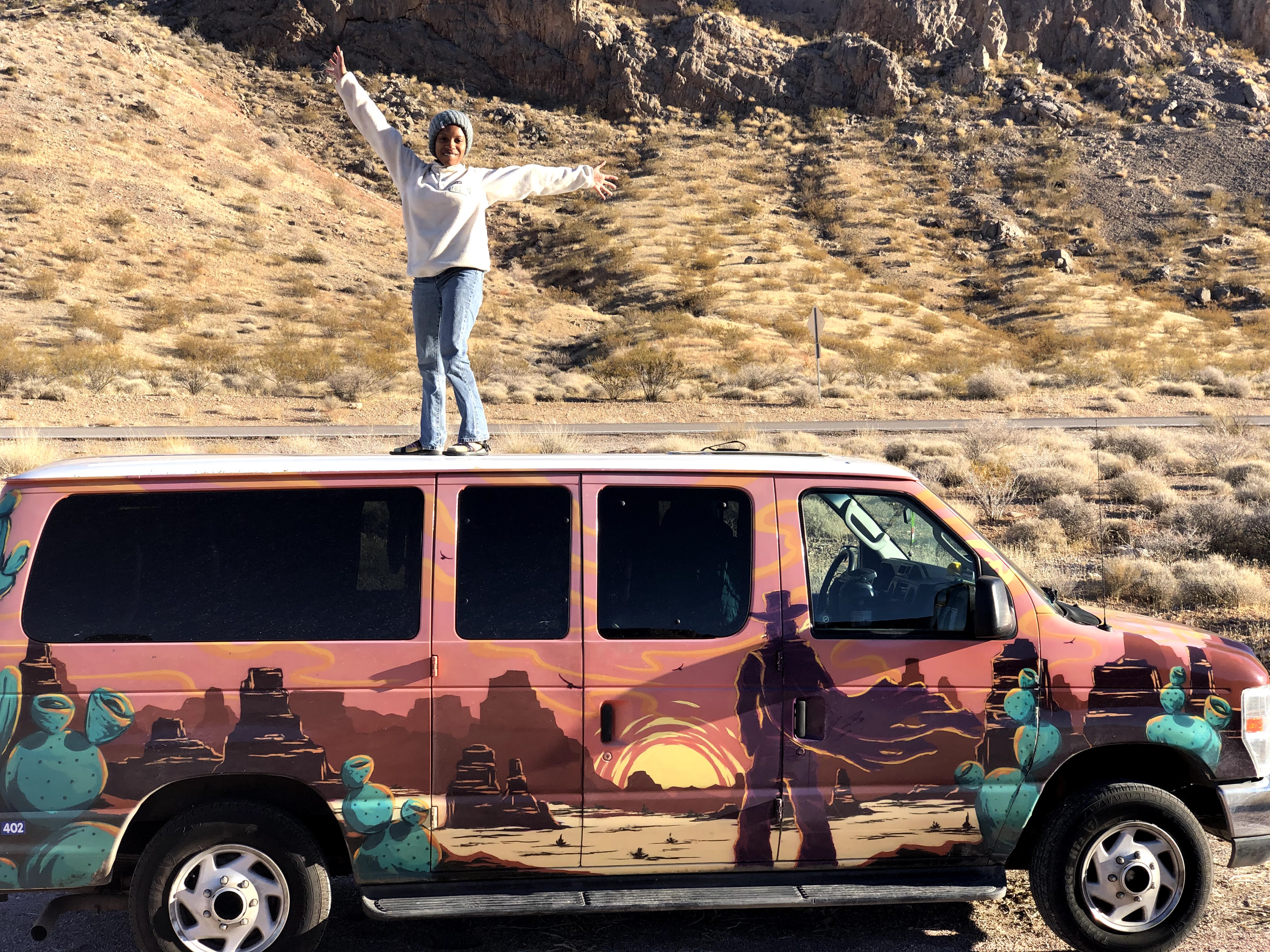 Woman standing on a van in desert
