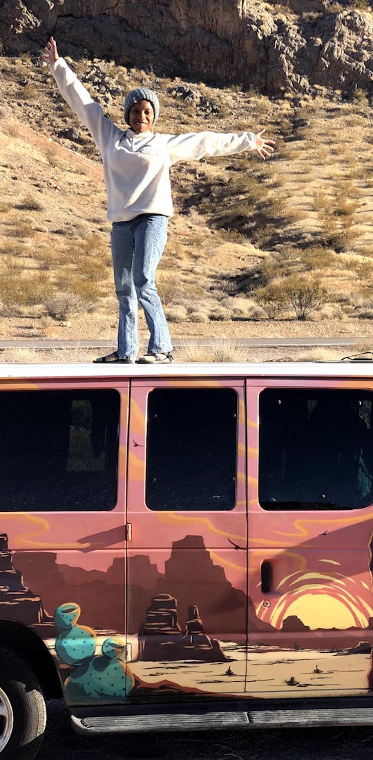 Woman standing on a van in desert