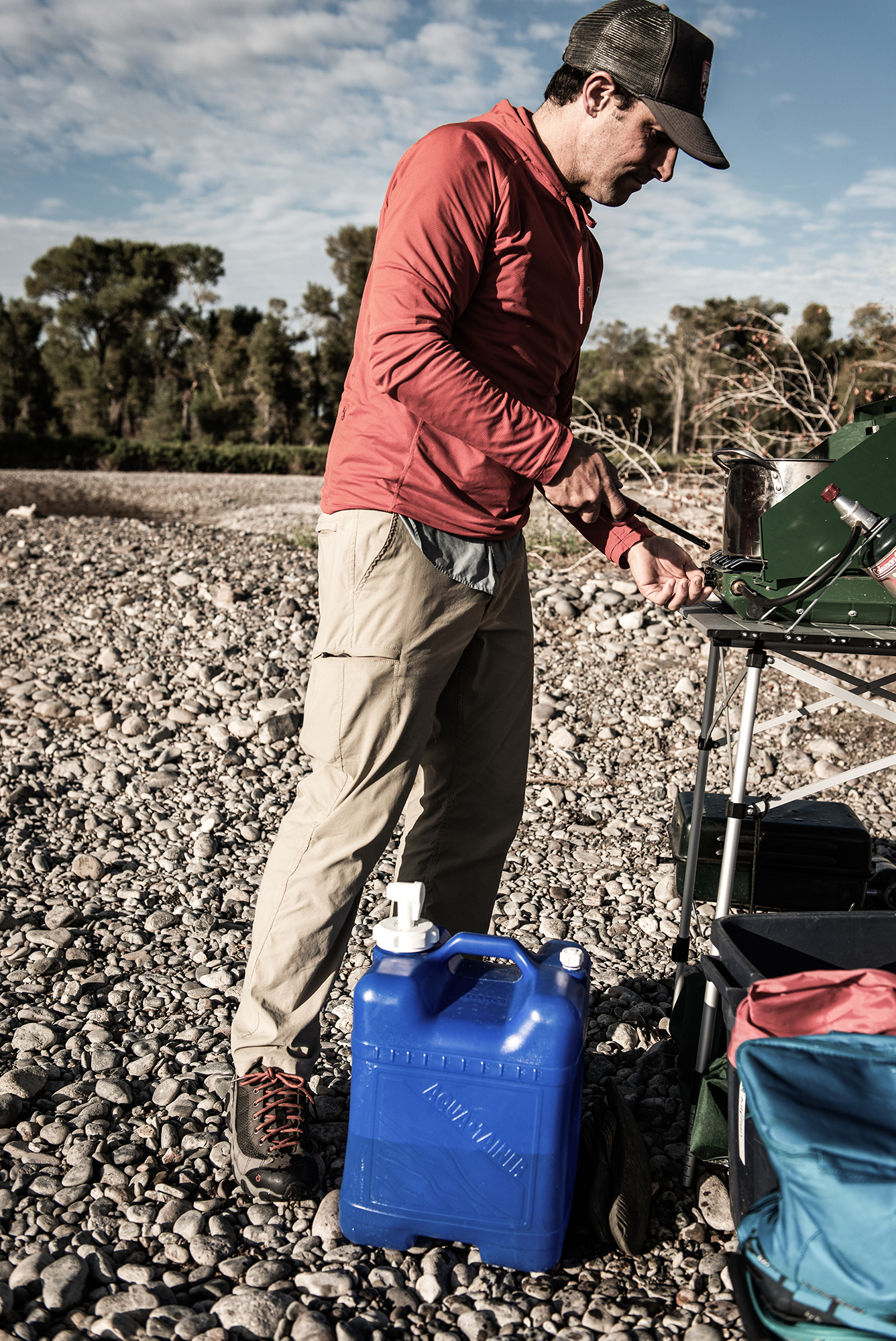 Man lighting a propane gas grill on a river trip.