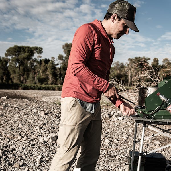 Man lighting a propane gas grill on a river trip.