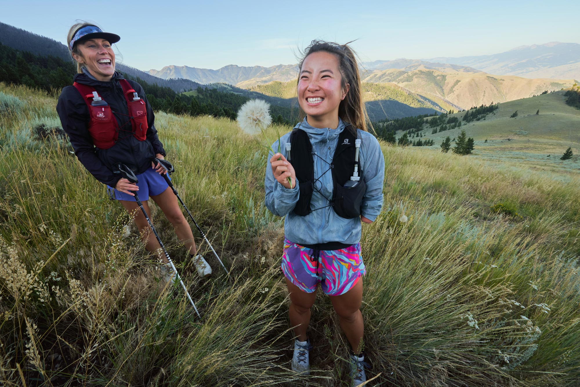 Woman holding a flower in a mountain meadow during her hike.