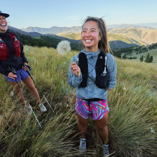 Woman holding a flower in a mountain meadow during her hike.