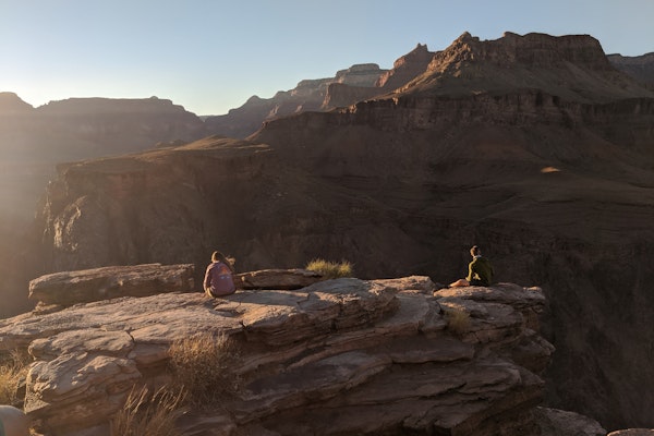 Two hikers overlooking a canyon on a bright, sunny day