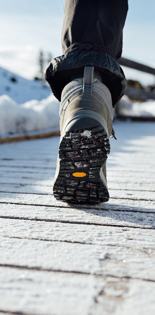 Oboz Andesite winter boot on a snowy wooden boardwalk.