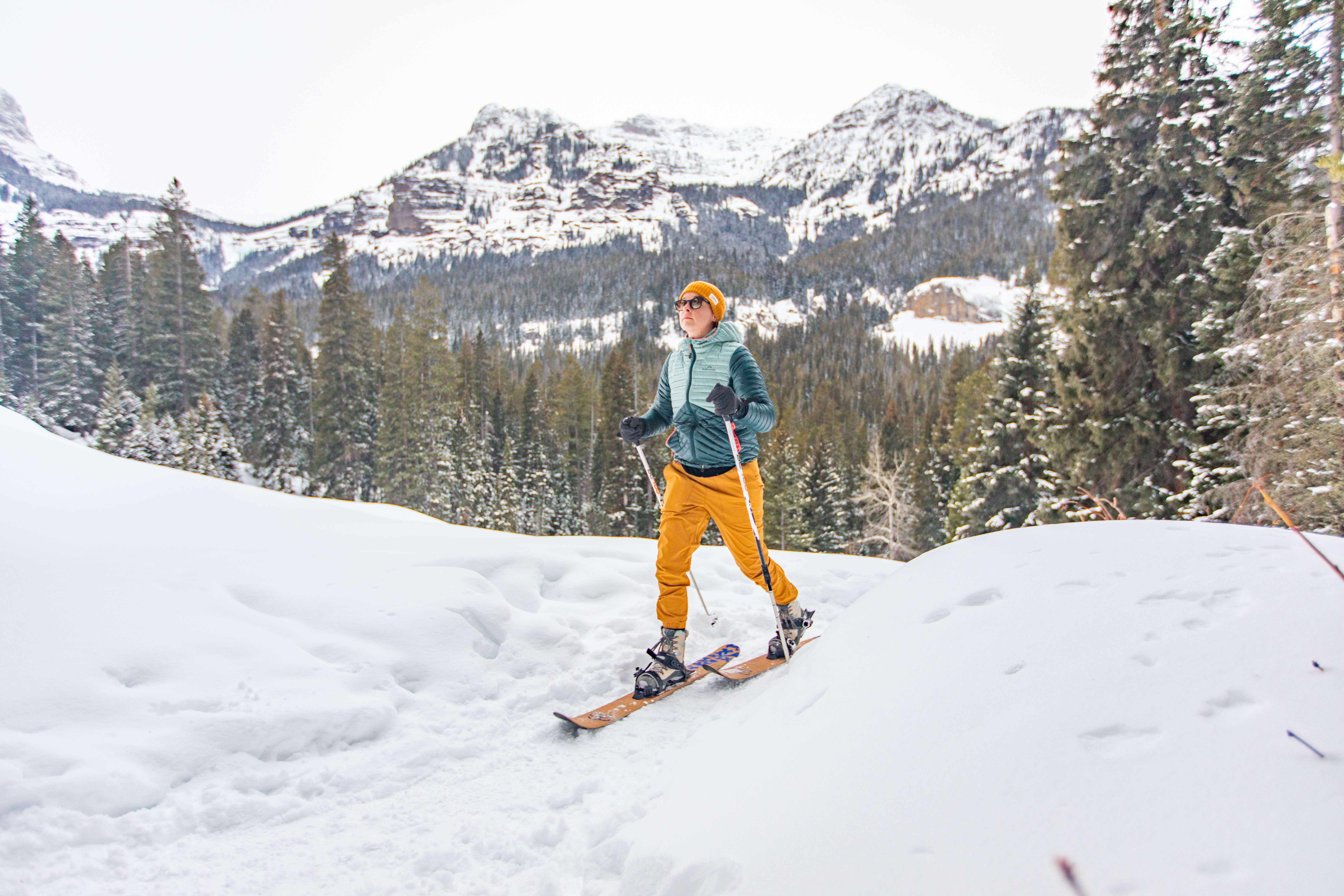 Woman backcountry skiing in on a snowy mountainous trail while wearing Oboz winter boots.