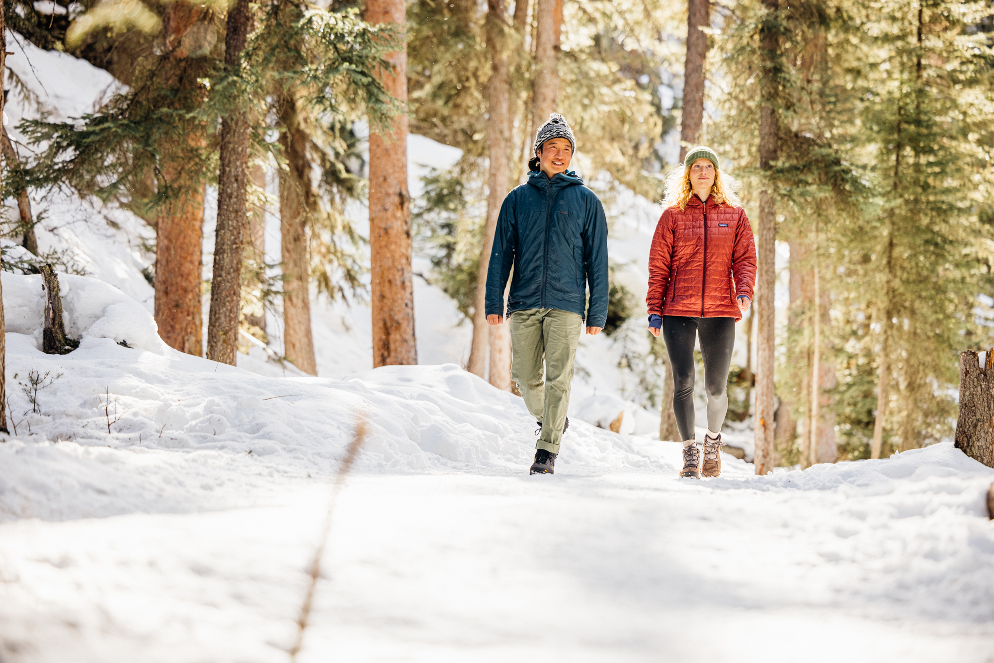A couple walking through the snowy forest in winter Oboz hiking footwear.
