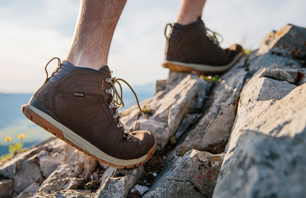 Man walking on rock in the Oboz Bozeman Mid Leather.