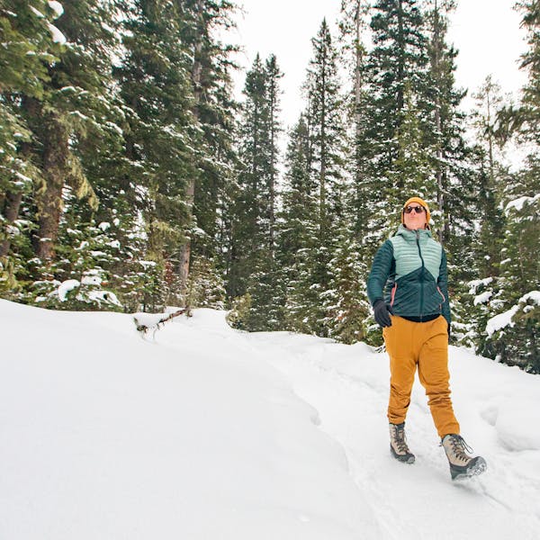 Woman walks through a snowy forest in Oboz Ousel winter insulated boots.
